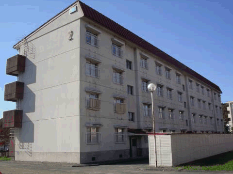 建物前に野外物置がある4階建て集合住宅の西ヶ丘団地2棟を左側から撮影した写真