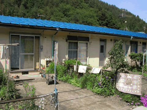 青い色の屋根で一戸建て住宅が隣り合わせで並んでいる平屋建て長屋住宅（1～3棟）の外観写真