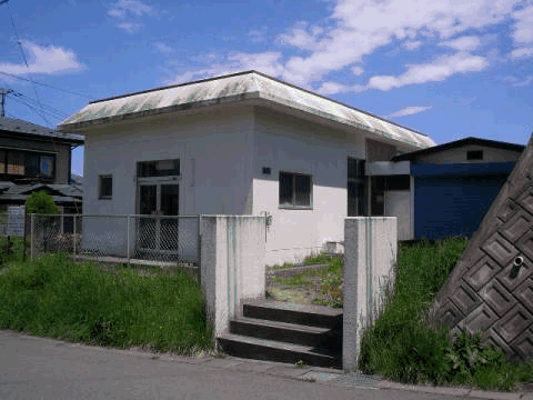 階段を上がった先にある白い外壁の日の出町団地住宅集会所の写真