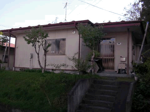 数本の木が植えられ、階段を上がった先にある平屋建て戸建住宅の外観写真