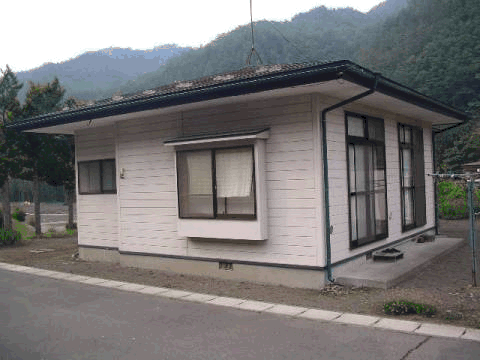 緑に囲まれ、道路沿いにある和美団地住宅の外観写真