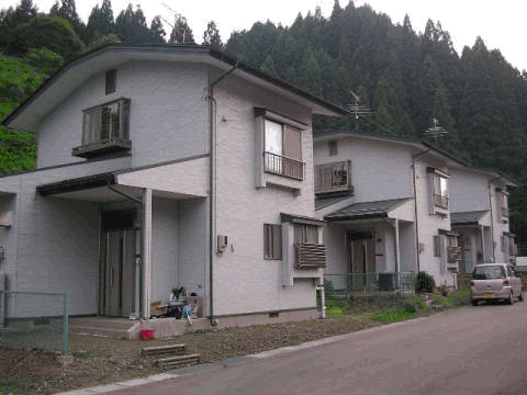 グレーの外壁で3棟並んでいる2階建て八坂団地住宅の外観写真