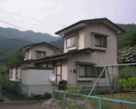 山の手前に建つ2階建て刈屋日向団地住宅の外観写真