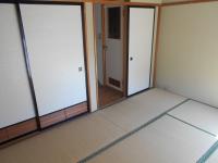 畳敷きの部屋の左側に襖があり、右側に奥へ続く廊下と扉が設置された内観の写真