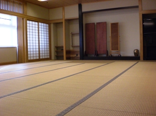 前方の姿見の左側にある障子と窓から光が差している和室の様子を右後方から撮影した写真