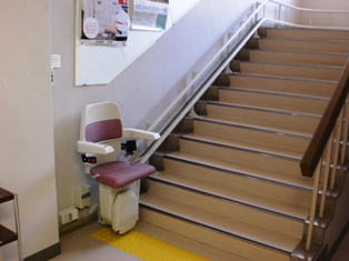 階段下に昇降用の椅子が設置された階段昇降機の写真