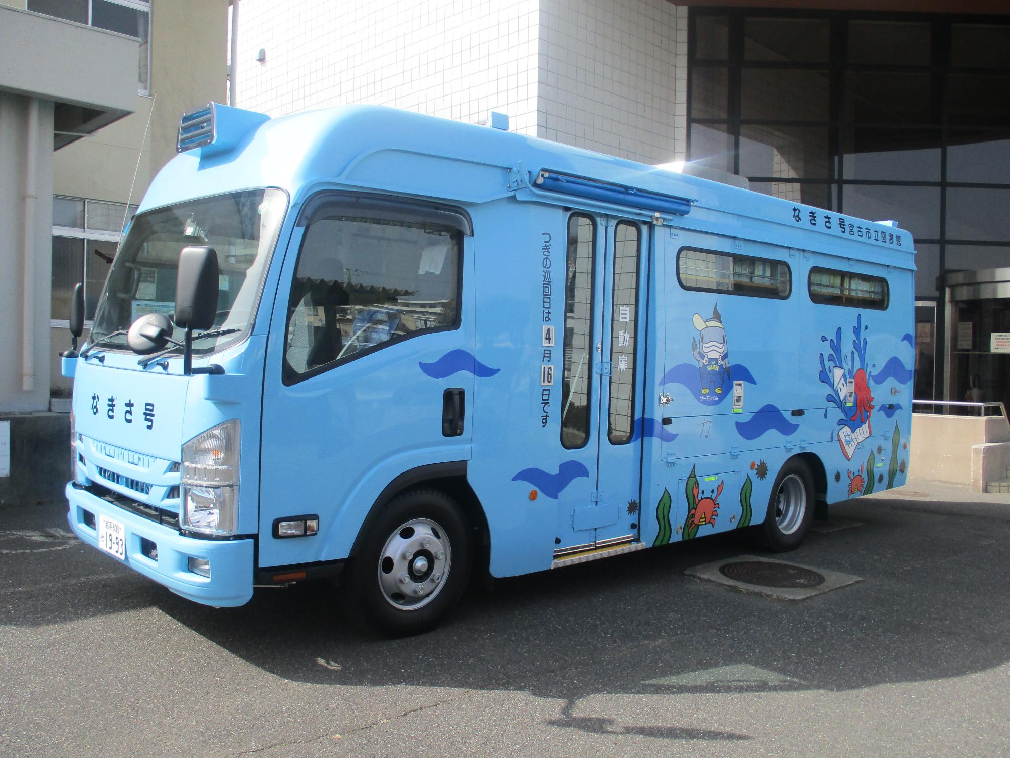 水色で海の中をイメージした塗装がされており車体のフロント箇所に「なぎさ号」とかかれているバスが建物前に停車している写真