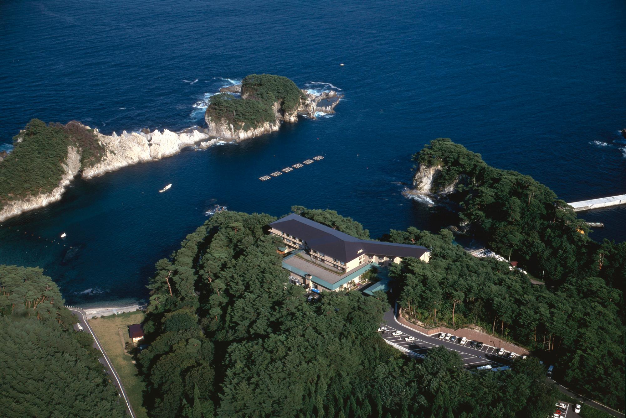 浄土ヶ浜がのぞめる高台に建築され周りを木々で囲まれた浄土ヶ浜パークホテルを上空から撮影した写真