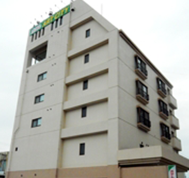 クリーム色の外壁で屋上にホテル名が書かれた看板が設置されているホテルアートシティの外観写真