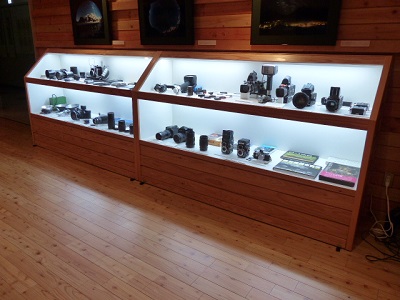 二段になった木製の展示ケースに、藤田氏が使用した貴重なカメラなどが展示されている様子を撮影した写真