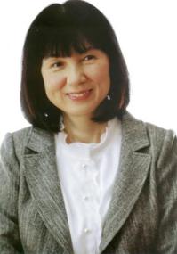 グレーのジャケットに白いブラウスの茂市久美子さんが微笑んでいる写真
