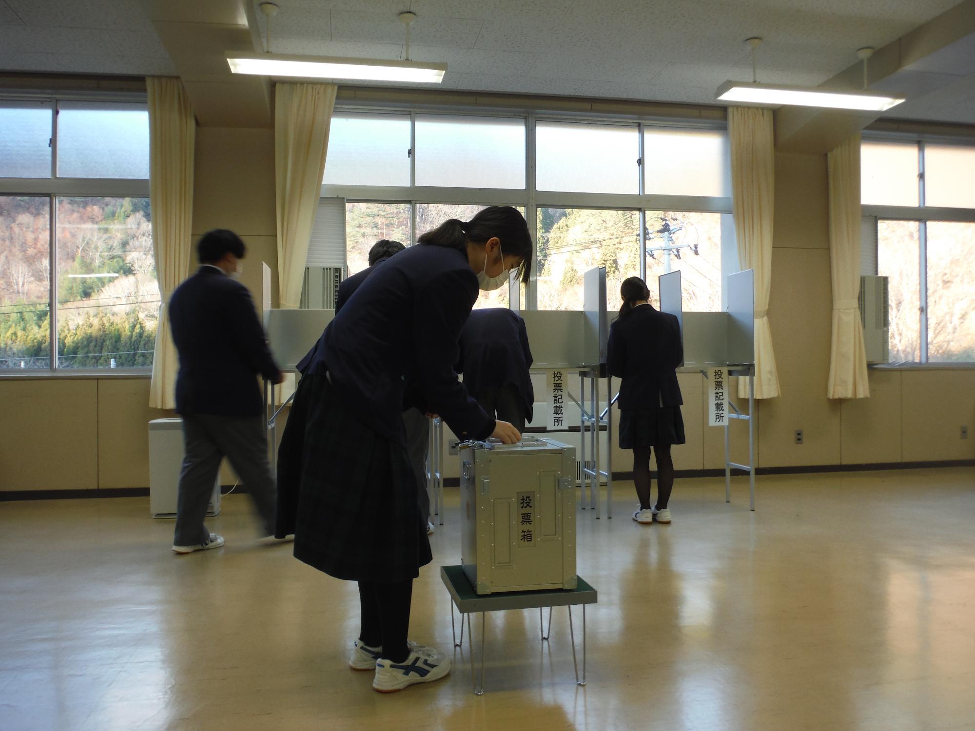 高校生スタッフが投票用紙を交付している写真