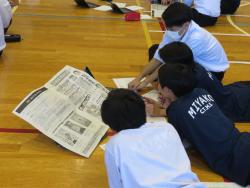 床に寝転がりながら新聞のようなものを見ている写真