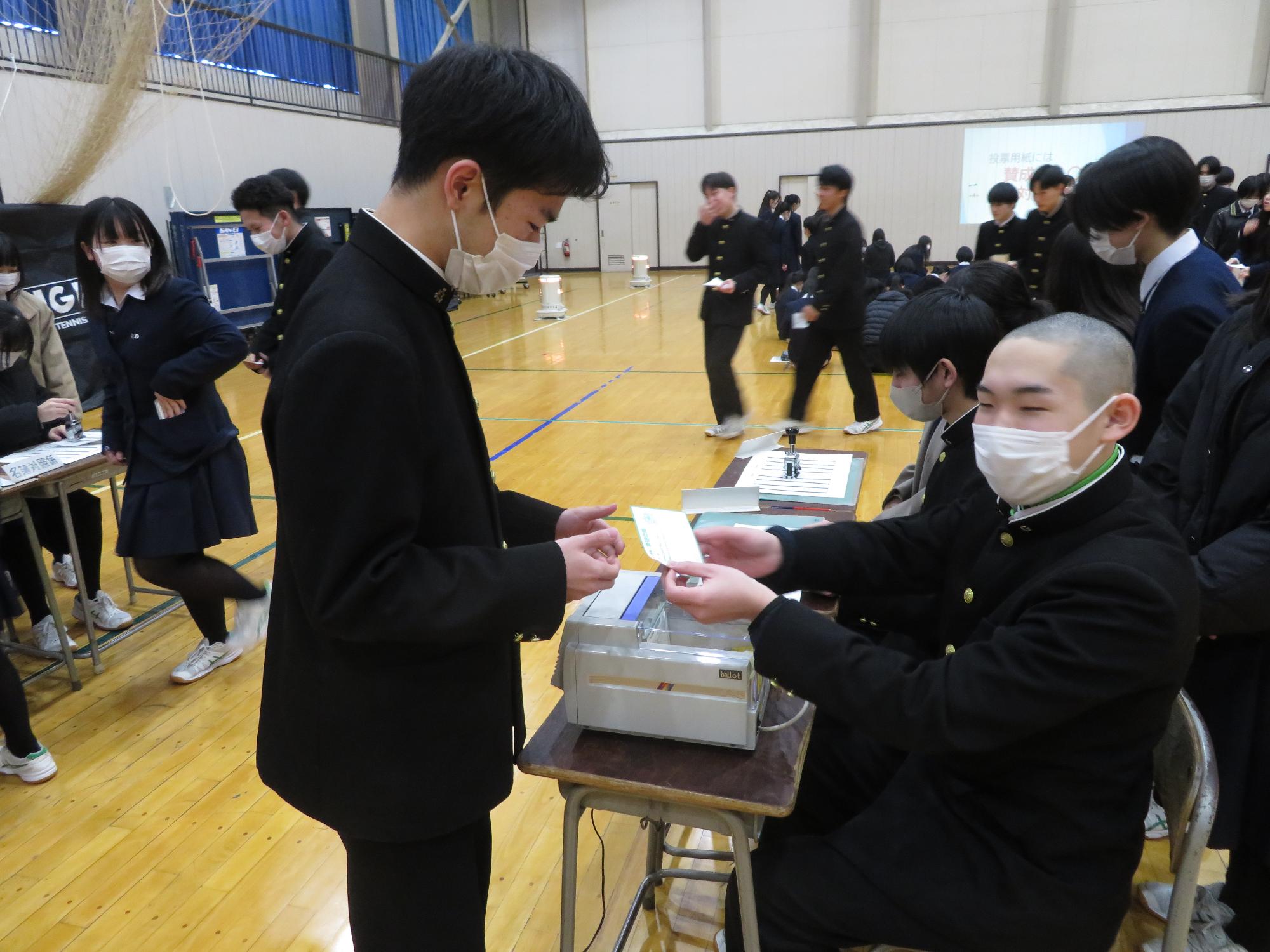 投票用紙を交付する高校生スタッフ