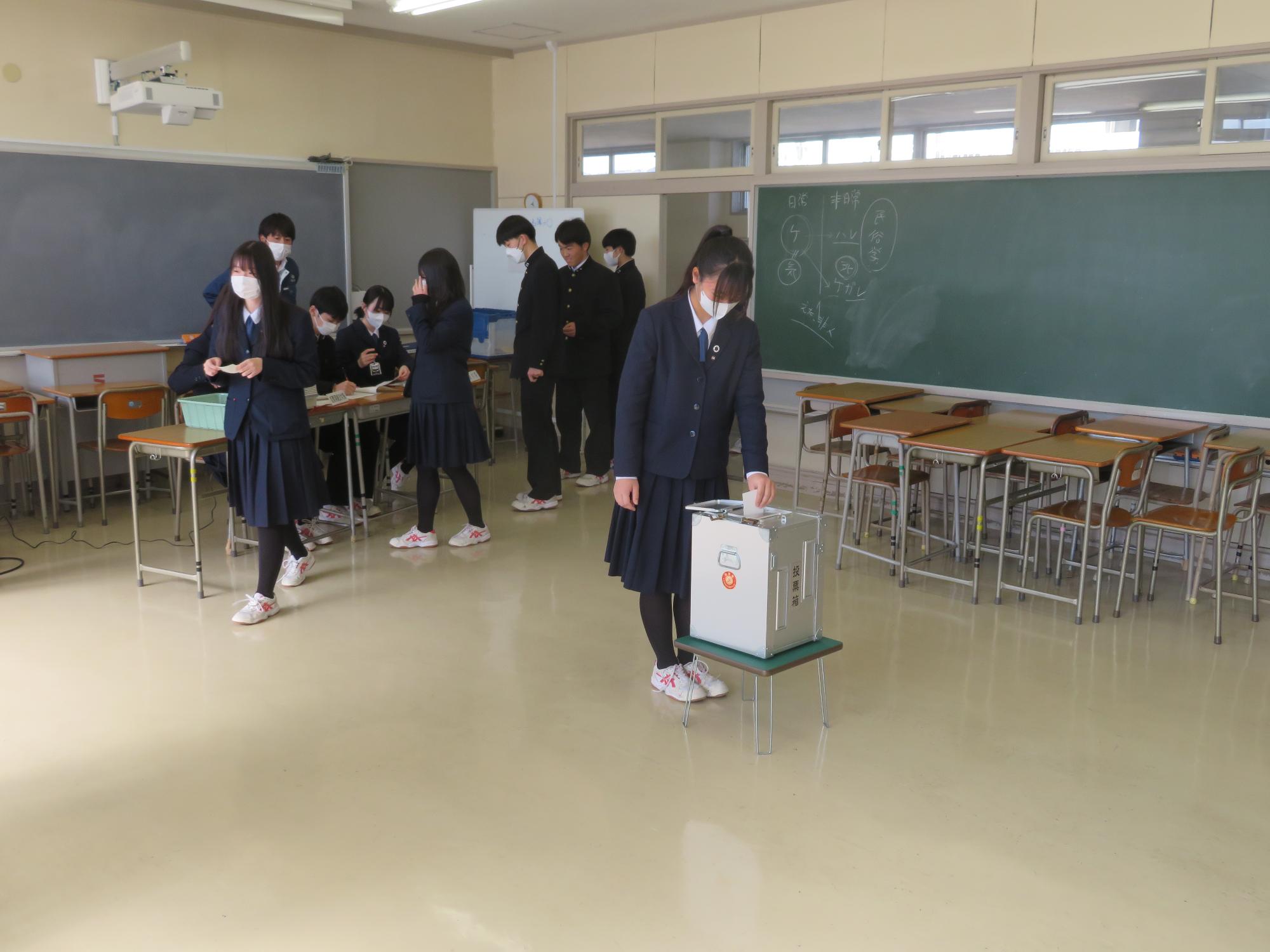 投票箱に投票用紙を投函する高校生