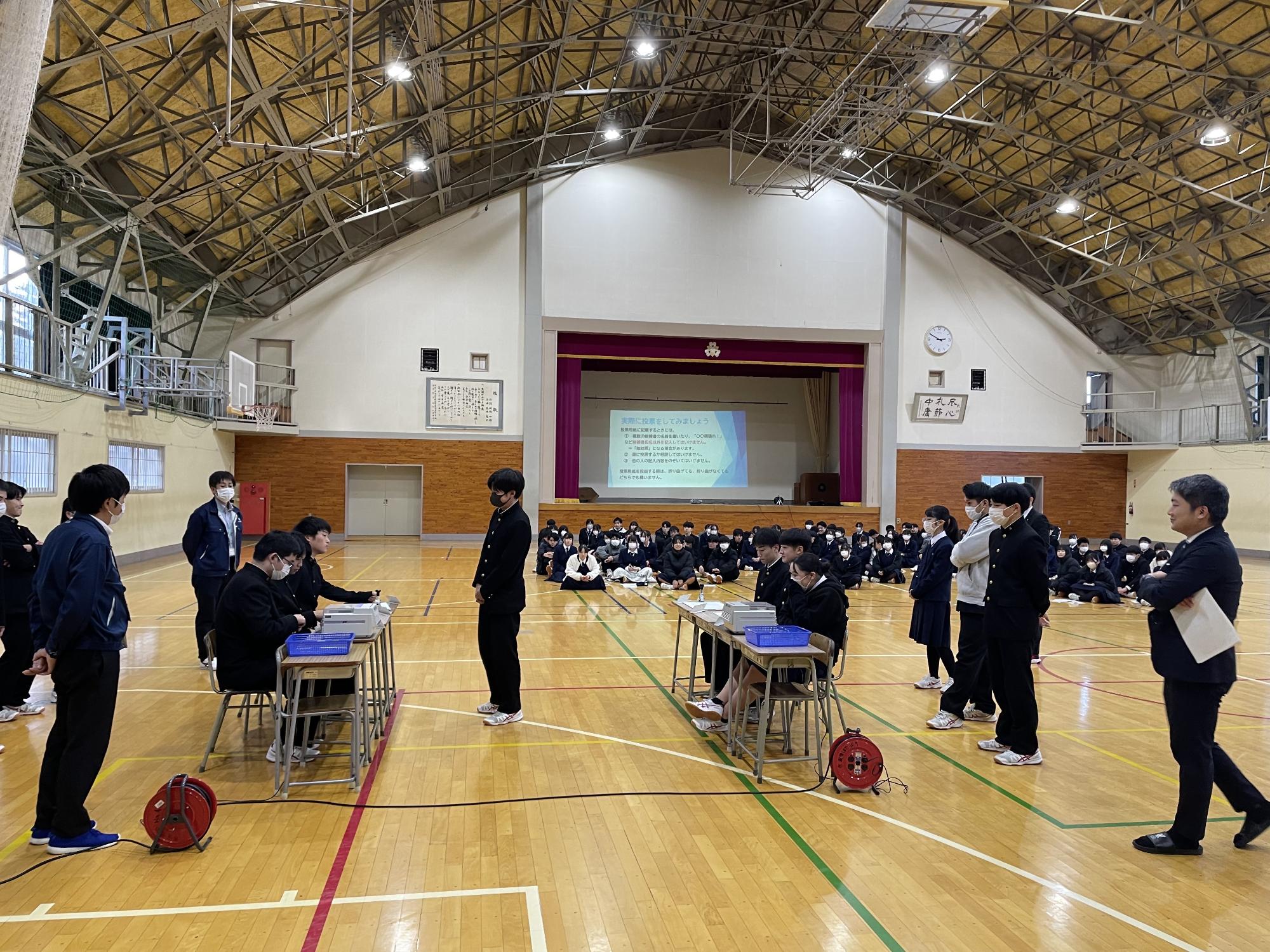 高校生が模擬投票所で受付をしている写真