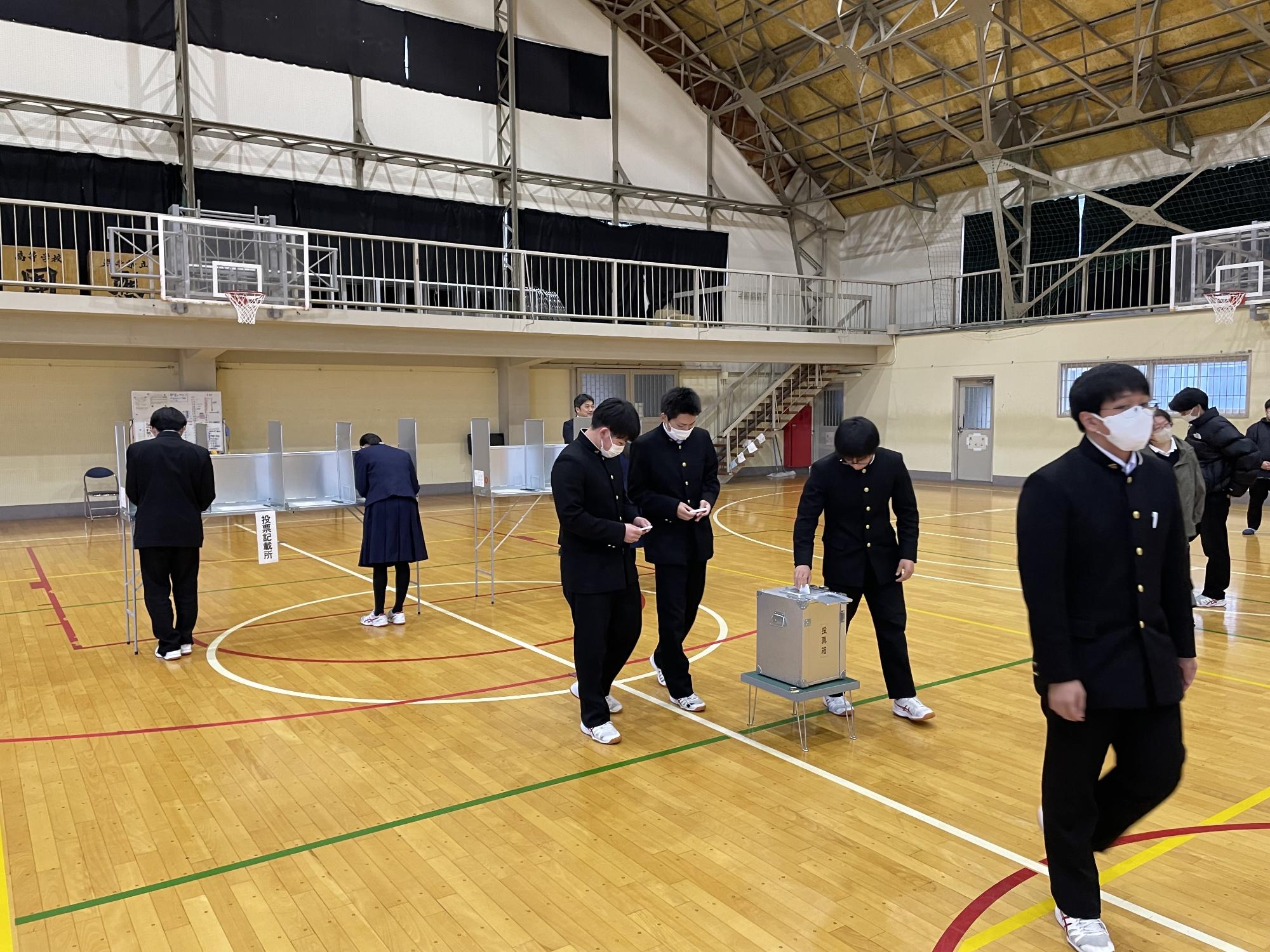 記載台で投票用紙に記入し、投票箱に投函する写真