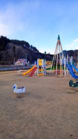 ロッキング遊具やすべり台付きの屋外遊具が設置された公園の写真