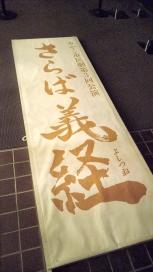 薄黄色地に中央に縦書きで「さらば義経」と書かれた看板の写真