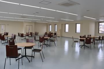 広いスペースに4脚ずつ椅子がセットされた8台の丸テーブルがランダムに置かれている様子を撮影した写真