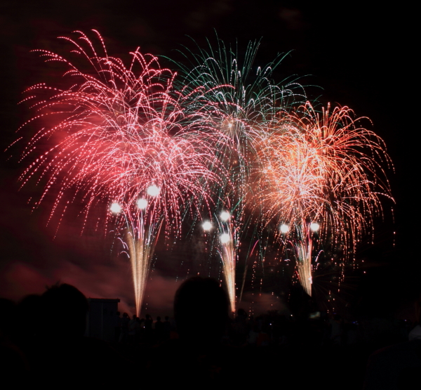 夜空に赤や青・オレンジ色の大輪の花火の写真