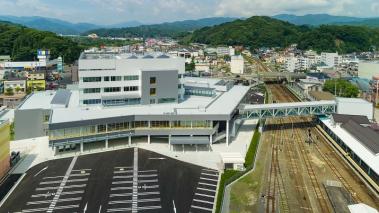 白い外壁で6階建ての宮古市市民交流センターイーストみやこと宮古駅前へ自由通路で結ばれている様子がわかる上空から撮影された写真