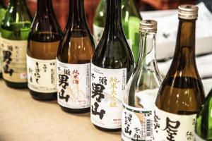テーブルの上に横一列に並べられた、様々な種類の瓶に千両男山と書かれた日本酒を斜め上から映した写真