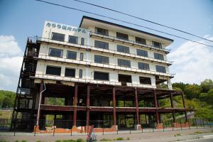 2階部分まで基礎がむき出しになっている、白い外壁の6階建てのたろう観光ホテルと書かれた建物の写真