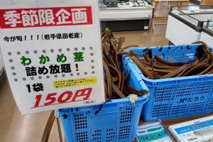 季節限企画と書かれたポップが付けられた青い籠に、わかめ茎がたくさん積まれている写真