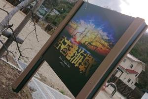 広場にある、夕日をバックにした鉄塔を背景に映画のタイトルのように黄色で宮古港海戦と書かれた看板の写真