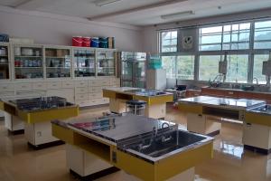 奥のほうに食器や料理器具の並んだ棚が、手前には調理用の机が映っている一室の写真