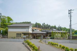 晴れた日の、背後に青々とした木々が生い茂っている、灰色の屋根をした山口公民館の写真