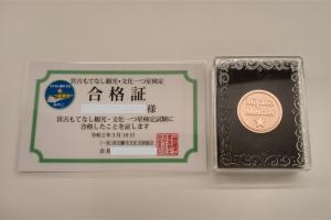 宮古もてなし観光・文化一つ星検定の合格証と、MiyakoMeisterの文字と一つ星が彫られたメダルが並んでいる写真