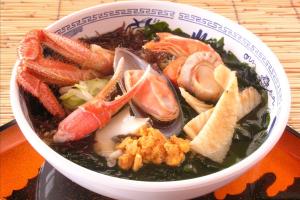 蟹や貝類、ウニ、わかめなどの海鮮がたくさんのせられた磯ラーメンの写真