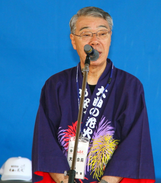 紫色の法被を着た市長がマイクの前で話をしている写真