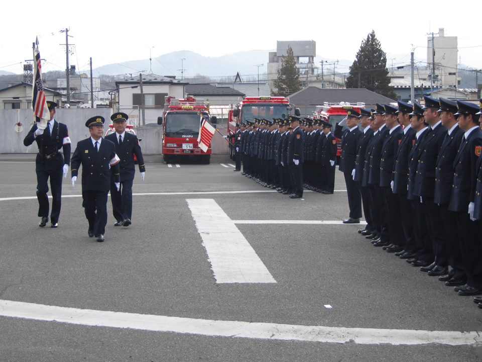 制帽と制服を身に着け整列する消防職員の前を歩く市長の写真
