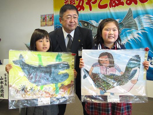 鮭の絵を両手で持つ2名の女子小学生と市長の記念写真