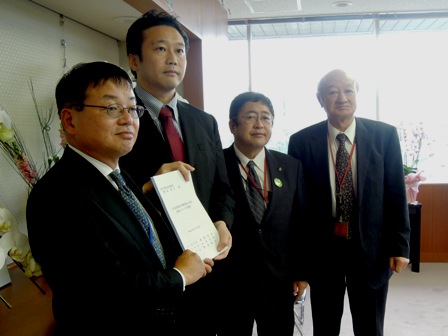 応接室のような部屋で、上野善晴岩手県副知事、橋本清仁国土交通大臣政務官、山本市長、伊達勝身岩泉町長が横一列に並んでおり、要望書を手に持っている写真