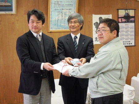 スーツを着た男性2名と市長が金封を一緒にもち記念撮影している写真