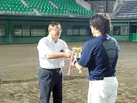 野球場で優勝した84夜球団の代表の方に、市長がトロフィーを渡している写真