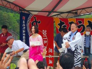 ピンク色の衣装を着た酒井法子さんと市長や関係者の方々が餅まきをする様子の写真