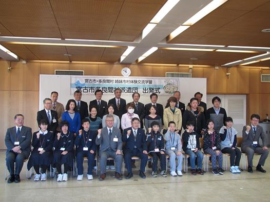 1列目に市長や小中学生、関係者の男性たちが椅子に座り、2列目3列目に関係者の方々が立って並んでいる記念写真