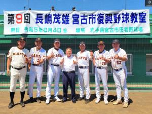第9回 長嶋茂雄 宮古市復興野球教室と書かれた横断幕の前に立つユニフォーム姿の巨人のOB6名と市長が並んで親指を立てるジェスチャーをしている写真