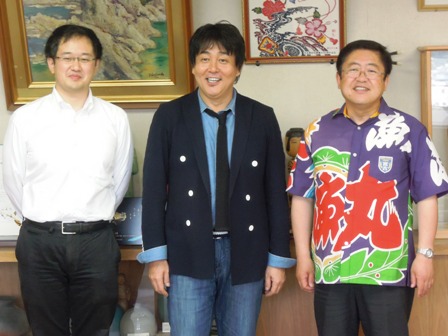 大漁旗柄のシャツを着た市長とTUBEの前田亘輝さんと関係者が3人で並んでいる写真