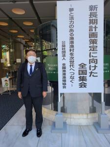 大きく「新長期計画策定に向けた全国集会」と書かれた立て看板の傍に立つ市長の写真
