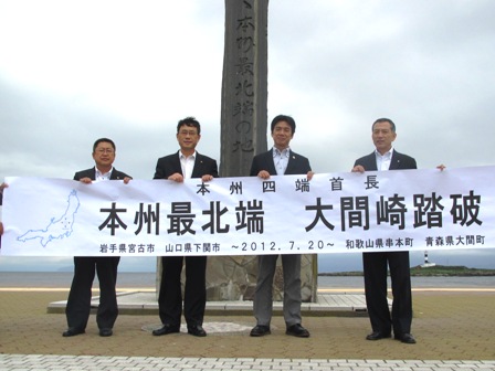 本州の最東西南北端に位置する4市町で構成する本州四端協議会の首長4名が並び、「本州最北端大間崎踏破」と書かれた横断幕を持って記念撮影している写真