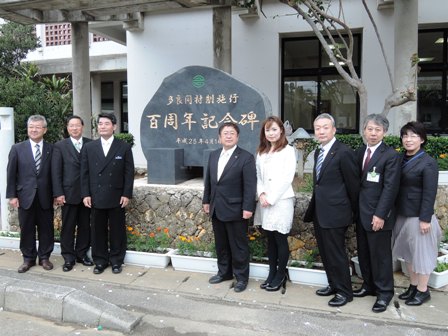 村制施行100周年の記念碑を背景にスーツを着用した市長を含む男女8名が記念撮影をしている写真