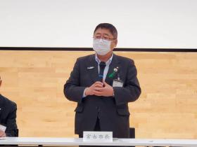 宮古市長と書かれた名札の席で立ち、市長が旧庁舎跡地公園について説明している写真