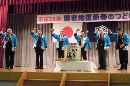 「平成25年田老地区新春のつどい」の吊り看板と、舞台上に置かれた樽酒の後方に、青いはっぴを着た市長と関係者が右手に枡を持っている写真