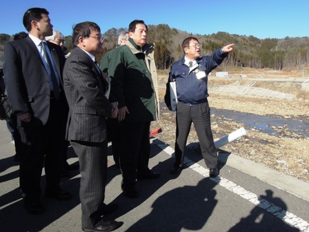 視察する太田昭宏国土交通大臣と関係者に向けて、市長が遠くを指をさしながら田老地区の状況を説明する写真
